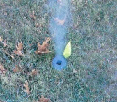 harmless white smoke coming from a 6-inch circular cleanout flush with the outside ground, which is grass