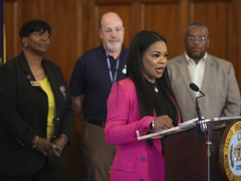 Tiffany Brown speaking at a lectern during a press conference
