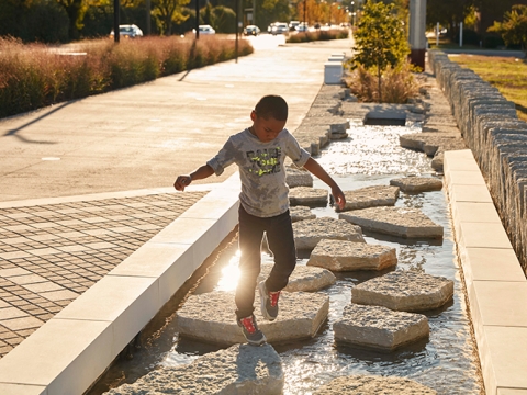 Young African American boy walking on stepping stones along the trail. 