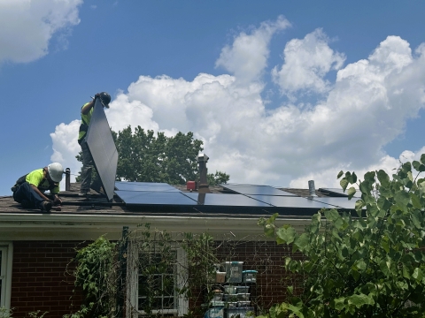 2 workers on the roof of a home installing solar panels on a sunny day 